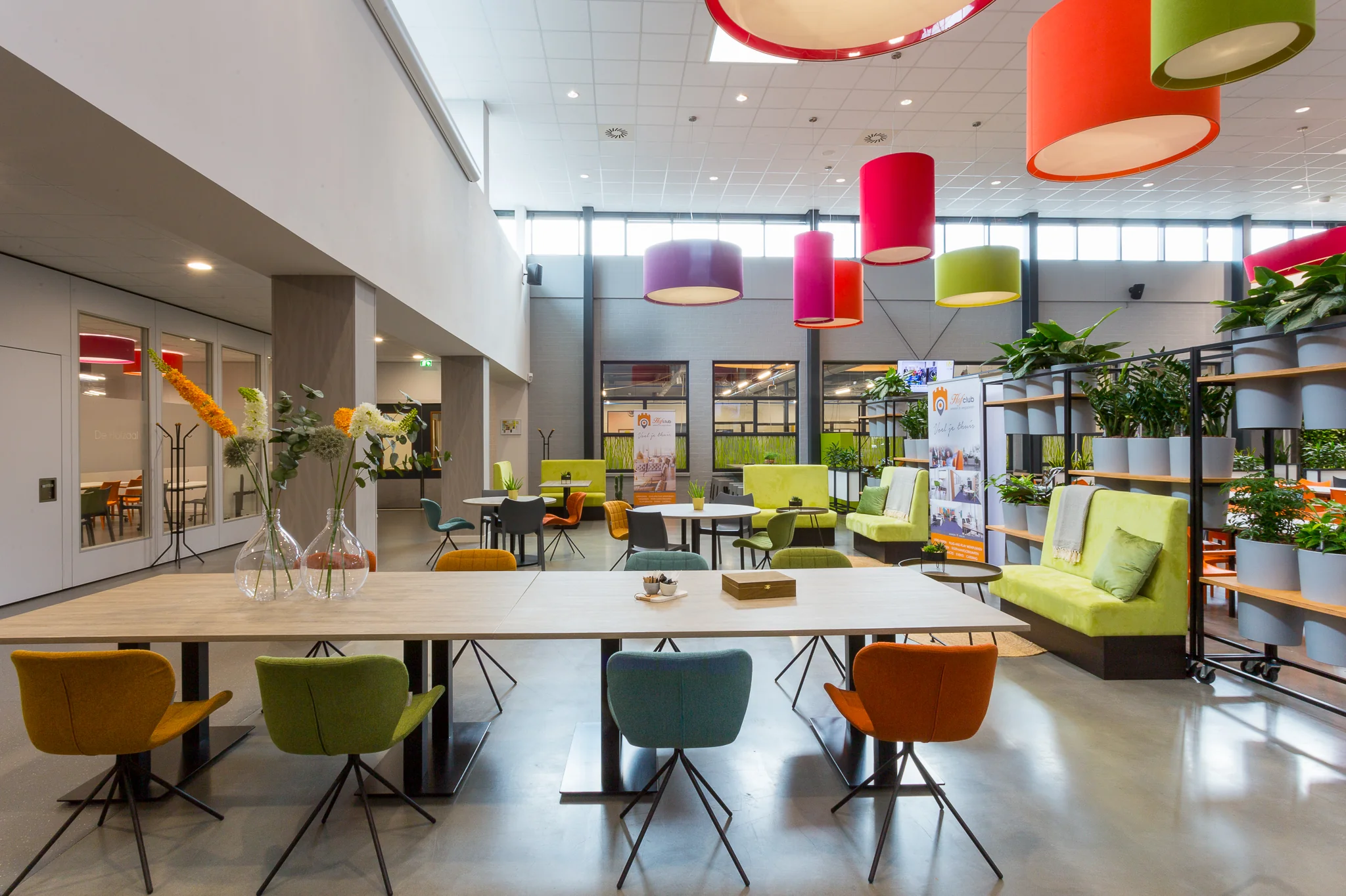 Moderne en kleurrijke ontmoetingsruimte aan de Niels Bohrweg met diverse zithoeken, planten en opvallende hanglampen.